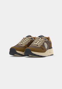 Sneaker in suede marrone e tessuto con accenti beige, punta rotonda, suola in gomma e lacci di colore chiaro. Logo sul lato e sulla linguetta.