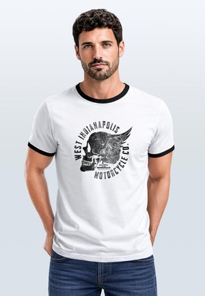 Mann mit dunklem lockigem Haar und Bart, der ein weißes T-Shirt mit schwarzem Saum und Totenkopf mit Flügel-Grafik und Text "West Indianapolis Motorcycle Co." trägt