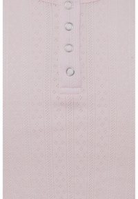 Světle růžový žebrovaný top s knoflíkovým henley výstřihem, zdobený malými dekorativními dírkami a pěti stříbrnými knoflíky.