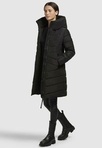 Black puffer coat with a high collar, zip closure, and side pockets. Smooth texture, knee-length design, and long sleeves.