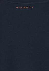 Námornícky modrá látka s malým, písaným hnedým textom "HACKETT" umiestneným v hornej časti uprostred.