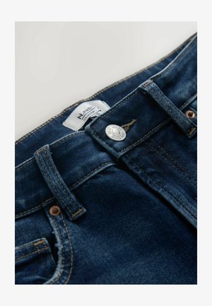 Sötétkék farmernadrág gombos záródással, övbújtatókkal és egy anyagcímkével a derékrész közelében. Az anyag sima textúrájú, minimális kopott hatással.