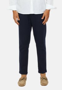 Pantaloni in cotone blu marina con vestibilità dritta, orli arrotolati e una texture liscia, abbinati a mocassini beige.