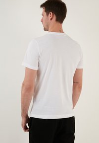 White cotton T-shirt with short sleeves and a crew neckline. Features a simple design, smooth texture, and a straight hem at the bottom.