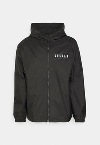 Czarna bluza z kapturem zapinana na zamek, z elastycznymi ściągaczami przy rękawach, ozdobiona białym napisem „Jordan” i subtelnym logo Jumpman na lewej piersi.