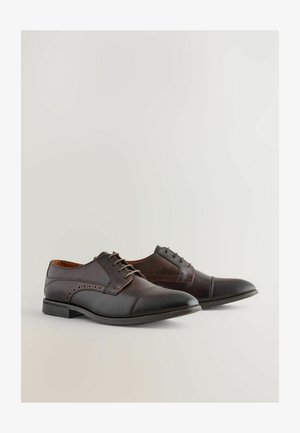 Dunkelbraune Lederschuhe mit glatter Oberfläche, spitzer Zehenform, strukturiertem Vorderkappenteil und dekorativen Perforationen an der Seite.
