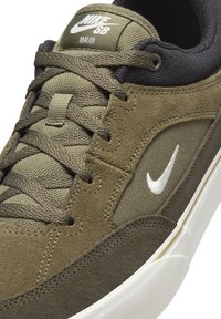 Zelené semišové a textilní tenisky s bílým logem Nike, mají kulatou špičku, ploché tkaničky a bílou gumovou podrážku.