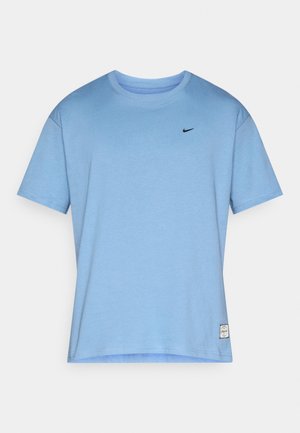 Šviesiai mėlynas medvilninis marškinėlis su apvalia iškirpte, trumpomis rankovėmis ir mažu juodu „Nike“ logotipu ant krūtinės. Apačioje yra etiketė.