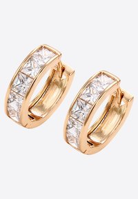 Des créoles en métal doré présentent une rangée de pierres en zircon cubique transparent sur le devant, avec une surface lisse et polie ainsi qu'un fermoir sécurisé.