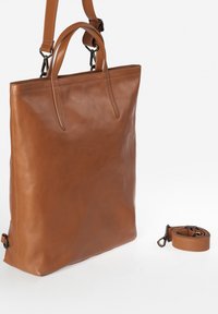Bruine leren tote bag met twee handvatten en een afneembare schouderband. Helle textuur, minimalistisch ontwerp en subtiele stikdetails.