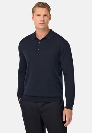 Polo a maniche lunghe blu navale realizzato in tessuto morbido, dotato di colletto classico, patta con tre bottoni e polsini a coste.