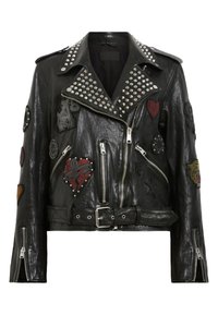 Black leather biker jacket with silver studs on collar, multiple embroidered patches, asymmetrical zipper, and belted waist.