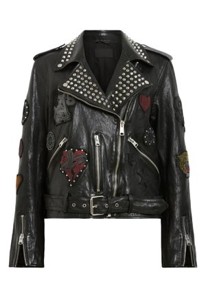 Black leather biker jacket with silver studs on collar, multiple embroidered patches, asymmetrical zipper, and belted waist.