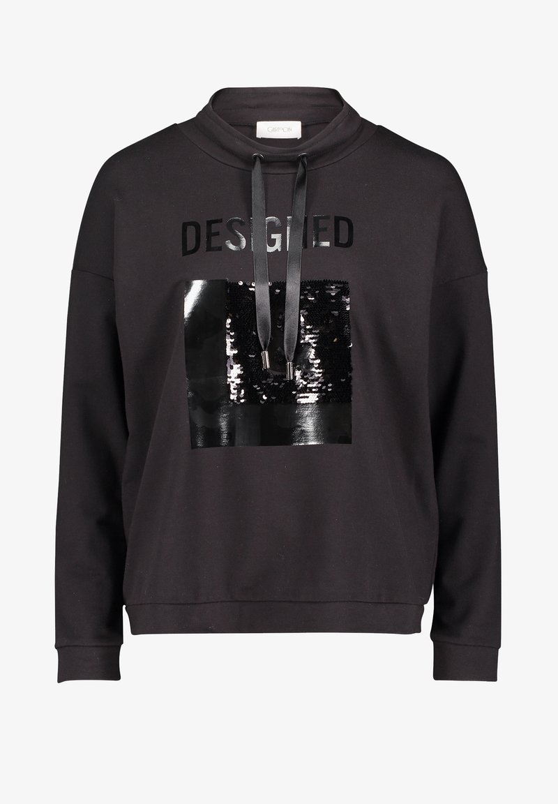 Sweat-shirt noir avec capuche à cordon, carré noir brillant à sequins, et le mot "DESIGNED" imprimé au-dessus du carré en lettres noires brillantes.