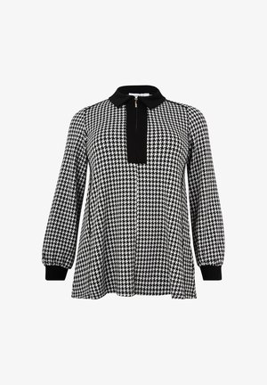 Zwart-wit houndstooth patroon blouse met een zwarte kraag, lange mouwen en een voorpand met een ritssluiting. Glad textuur.