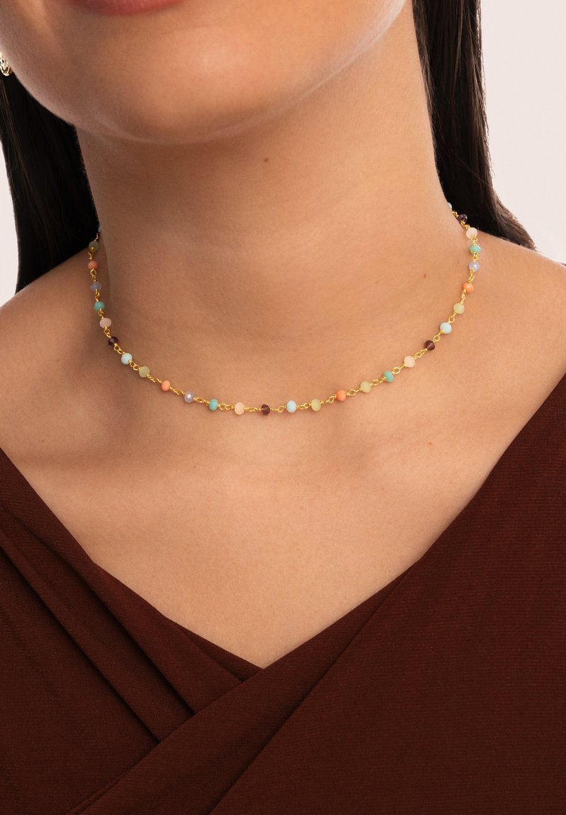 Farbige Perlen-Choker mit einer goldenen Kette, die kleine, mehrfarbige Perlen in Pastellnuancen zeigt. Glatte Textur, zartes Design, sitzt am Hals.