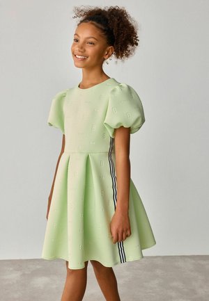 Kurzärmliges, mintgrünes Kleid mit strukturierten B-Mustern, plissiertem Rock und schwarzen Streifen an den Seiten. Glattes Material mit strukturiertem Schnitt.