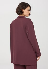 Bordowa koszula z długim rękawem, z kołnierzykiem, luźny krój i mankiety zapinane na guziki. Gładka tekstura i prosty dół, zaprojektowana z myślą o luźnej sylwetce.
