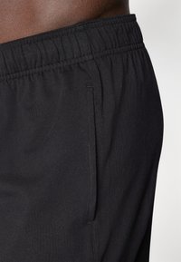 Black athletic shorts featuring an elastic waistband and side pocket. The fabric has a smooth texture with a consistent color.