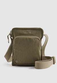 Small olive green Levi's crossbody bag with front zip pocket, adjustable beige strap, and textured fabric.