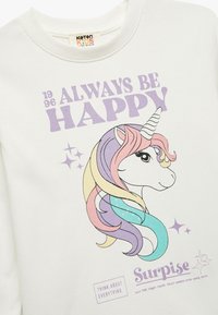 Hvid bomulds sweatshirt med et enhjørning-grafik med farverig manke, teksten "ALWAYS BE HAPPY" og glimmer, designet til børn.
