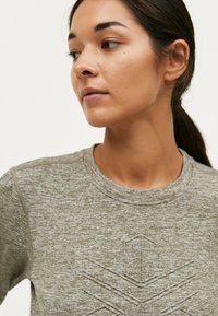 Lys brun, tekstureret sweatshirt med rund halsudskæring og subtilt geometrisk mønster. Har lange ærmer og en afslappet pasform.