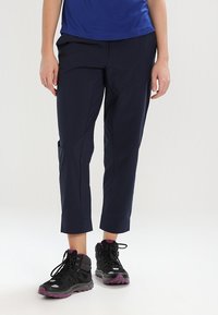 Merijapan penkki hameet suoran leikkauksen omaavat, joissa on sivutaskut ja sileä pinta, yhdistettynä mustiin vaelluskengiin, joissa on violetteja yksityiskohtia.