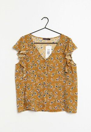 Musztardowa bluzka z dekoltem w kształcie litery V i falbanistymi rękawami, zdobiona kwiatowym wzorem w różnych kolorach oraz subtelnymi pionowymi paskami.