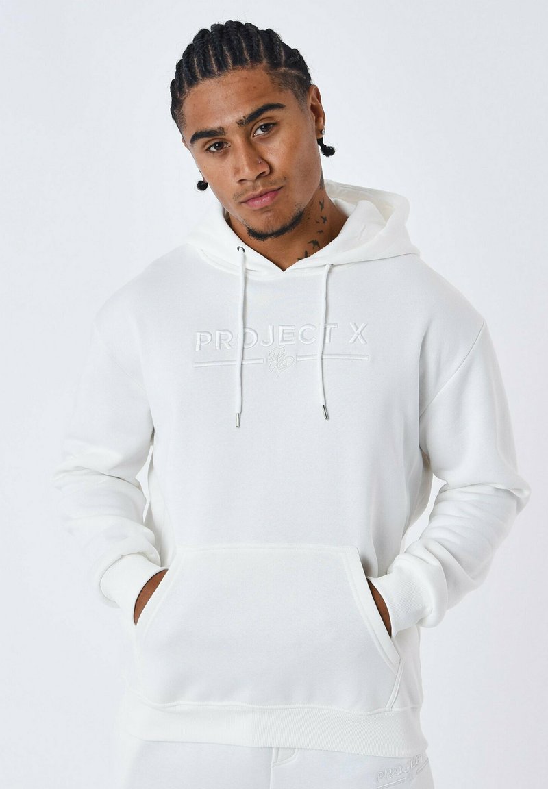 Sudadera blanca con capucha hecha de tejido suave. Presenta un bolsillo frontal, puños acanalados y un logo en relieve en el pecho. Diseño simple.