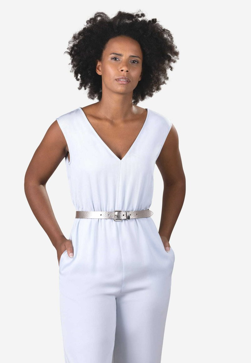 Un ensemble bleu clair avec un décolleté en V profond et un design sans manches. Il présente une ceinture texturée argentée à la taille et des poches de chaque côté.