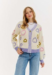 Krémový cardigan s vícebarevnými srdíčky, který má jemnou texturu, fialový lem a čtyři knoflíky vpředu. Vhodný pro neformální nošení.