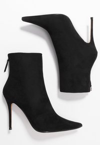 Bottes cheville en daim noir avec un bout pointu, une silhouette élégante et un talon stiletto haut. Équipées d'une fermeture éclair latérale pour un enfilage facile.
