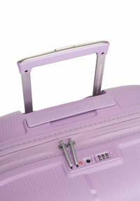 Paars harde koffer met ribbelstructuur, zilveren telescopische handgreep, dubbele ritssluitingen en een ingebouwd cijferslot aan de zijkant.