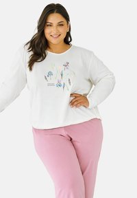 Biały top z długim rękawem w kwiatowy wzór w odcieniach niebieskiego i zielonego, zestawiony z różowymi spodniami. Materiał bawełniany, luźny krój, okrągły dekolt.