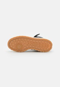 Crna đonika od tenisica s teksturiranim smešanim gumenim dnom, koje sadrži kružne i heksagonalne uzorke. "Adidas" logo vidljiv na strani.