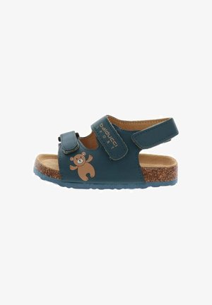 Sandale bleue pour enfants avec brides réglables, semelle en liège et motif d’ours en peluche sur le côté.