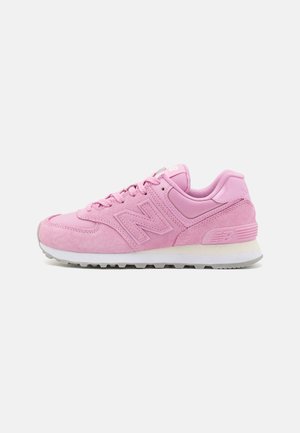 Różowe buty sportowe New Balance z cholewką z zamszu i siateczki, białą śródpodeszwą, szarą podeszwą zewnętrzną oraz logo na boku i pięcie.