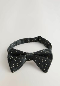 Black bow tie made of smooth fabric, featuring a polka dot pattern in off-white. Adjustable strap with a textured finish.