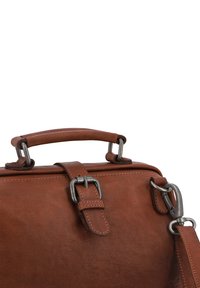 Bruine leren tas met een gestructureerde afwerking, voorzien van een handvat aan de bovenkant, metalen beslag en een verstelbare riem met een clip.