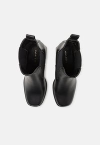 Bottines noires en cuir avec un design épuré, bout carré, panneaux latéraux élastiques et tirant à l'arrière. L'intérieur est doté d'un revêtement doux.
