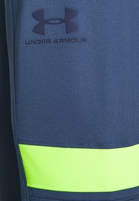 Pantalones cortos deportivos de la Marina hechos de tela texturizada. Presentan una franja de acento en verde lima y el logo de Under Armour en azul marino oscuro.