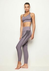 Set di reggiseno sportivo e leggings color lavanda chiaro con accenti neri e motivi a strisce, realizzato in materiale elastico, design aderente.