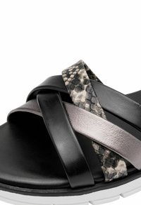Sort sandal med en hvid sål har tre krydsende remme: en blank sort, en metallisk grå og en struktureret slangeskindspræget i grå og sort.