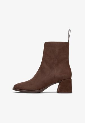 Stivaletto in pelle marrone, con una texture liscia, punta affusolata e tacco quadrato. Presenta un anello sul retro per indossarlo facilmente.