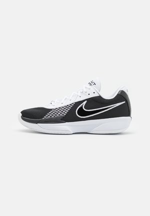 Des chaussures de sport Nike en noir et blanc avec une tige en mesh, un talon noir texturé et un logo swoosh blanc proéminent sur le côté.
