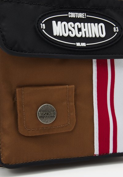 Geantă Moschino cu un capac negru, un corp maro, dungi roșii și albe și un buzunar frontal cu un accent metalic rotund ce reprezintă logo-ul.