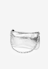 Bolso de mano metálico plateado con un acabado liso, forma curva y una correa de cadena. Cuenta con un cierre de cremallera para un acceso fácil.