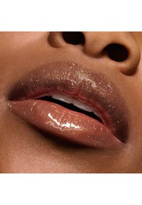 Læbepomade med en gradient fra blød brun til glitrende guld, med en glansfuld finish og subtil funklende effekt, der fremhæver den naturlige læbetextur.