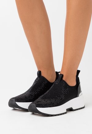 Svarta mesh sneakers med en texturerad ovandel, som har en vit kraftig sula och svarta detaljer, perfekta för avslappnad klädsel.
