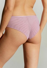 Slip hipster di colore rosa chiaro, senza cuciture, con una texture liscia e un design minimalista. Caratterizzati da un taglio a vita bassa e una cintura morbida.